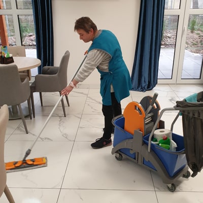 Gebäudereinigung in Frankfurt am Main, die Mitarbeiterin macht den Boden im Esszimmer sauber